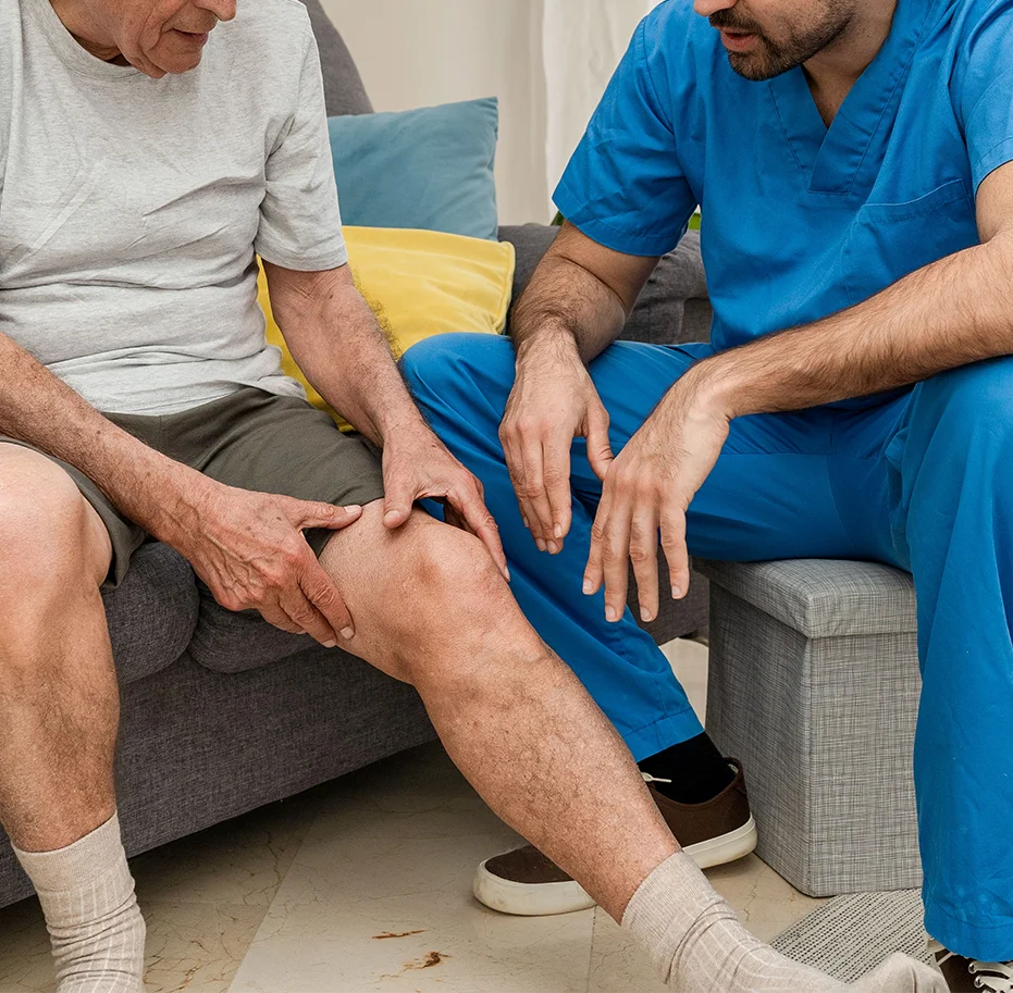 Fisioterapeuta valorando la rodilla de un paciente mayor en su domicilio